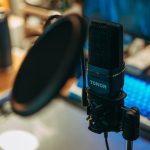 Close-up of a modern studio microphone with pop filter on a desk, perfect for recording.